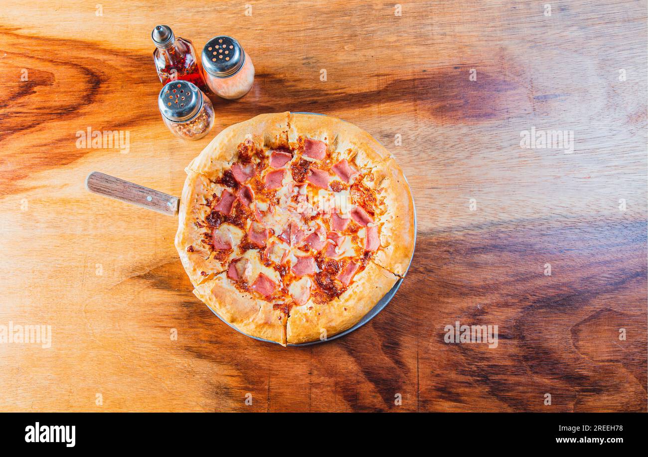 Ham pizza with cheese edge on wooden background. Top view of ham and