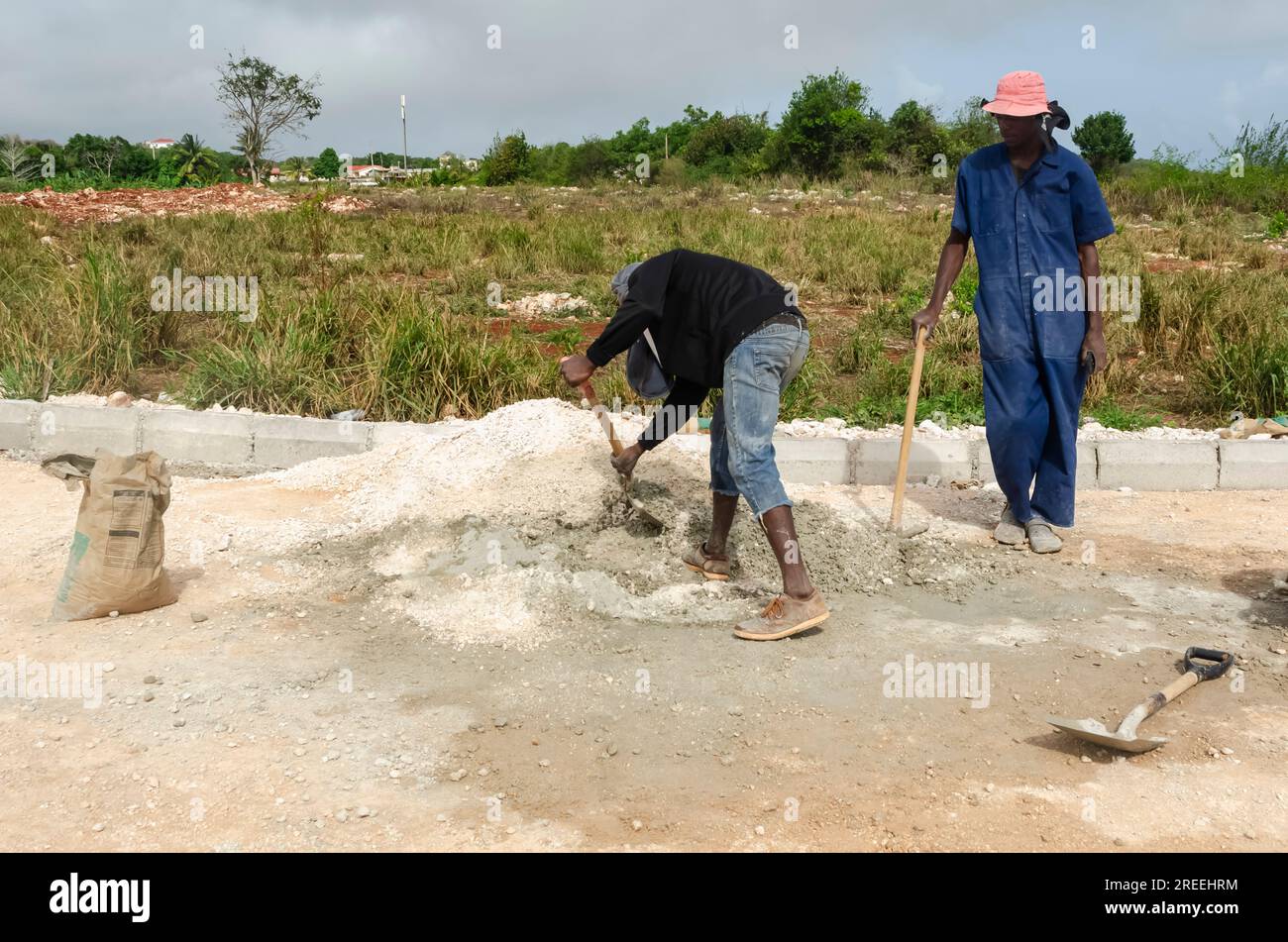 Standing And Looking At A Worker Mixing Mortar Stock Photo