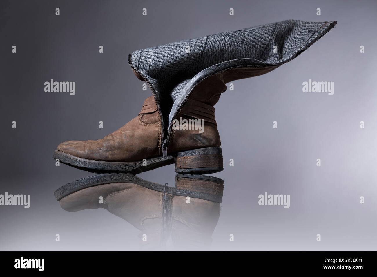 Old, damaged female boots with gray background Stock Photo - Alamy
