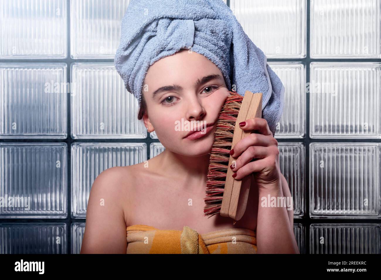 Sad woman cleaning her face with a huge scrubbing brush Stock Photo