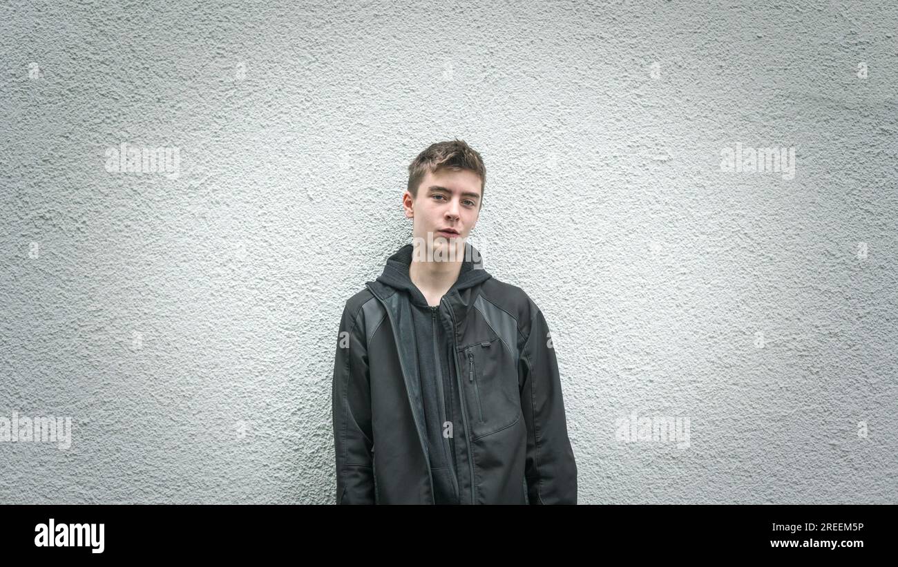 Portrait of a young man leaning against a white wall Stock Photo - Alamy