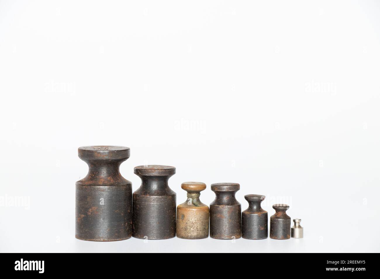 Old rusty weights for scales of different sizes and weights on a white