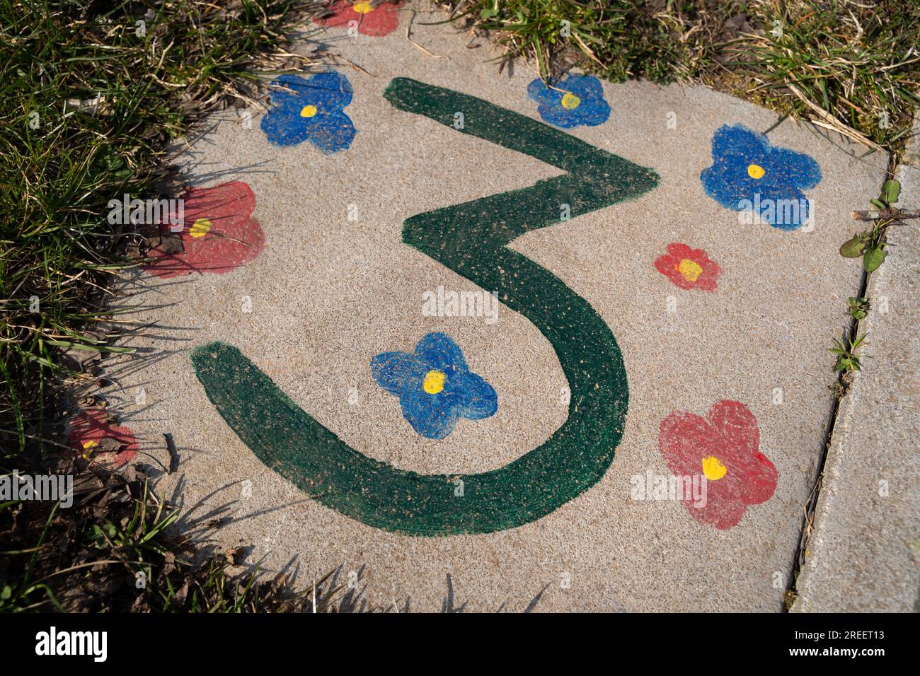 Hopscotch game painted by children on the playground with a green number 3 and coloful flowers Stock Photo