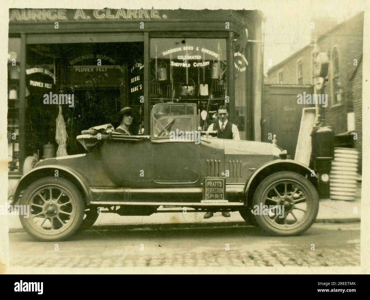 Original 1920's era small postcard Maurice A. Clarke Ironmongers / hardware shop -small family run business -  proprietor's wife sits in car, Morris Cowley 'Bullnose' open 2 seater - possibly showing off the new family car. London U.K. Circa 1925. Stock Photo