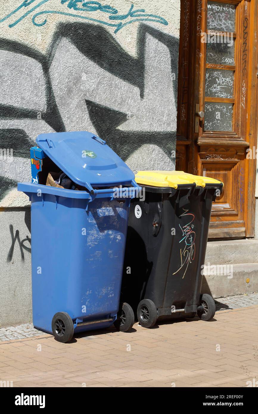 Blue bin for waste paper and yellow bin for plastic waste standing on the street, waste