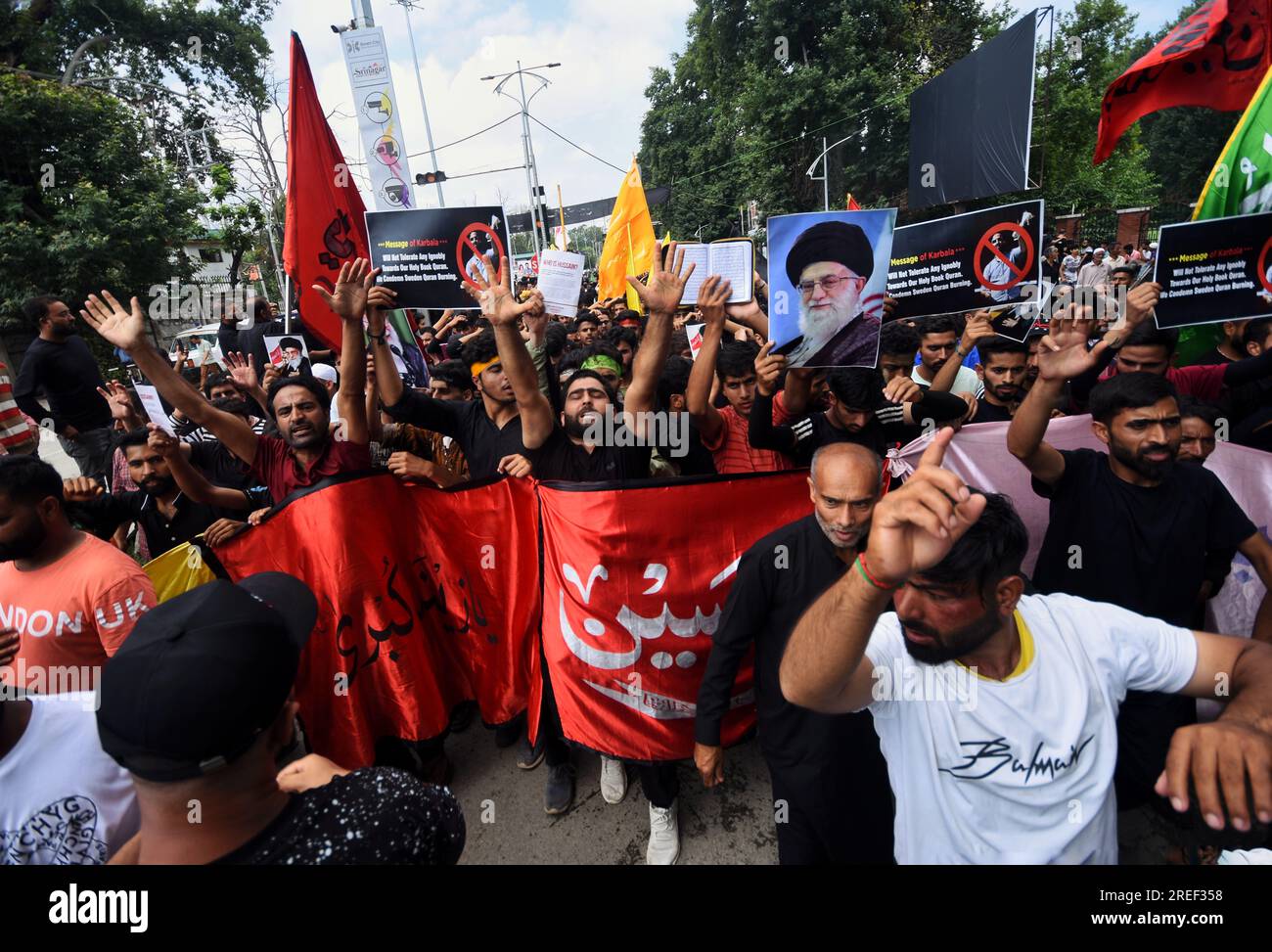 SRINAGAR, JAMMU AND KASHMIR, INDIA - 2023/07/27: Kashmiri Shia Muslims hold  portraits of Iranian leader and the Quran denouncing the burning of Islamic  holy book Quran in Sweden during a procession on