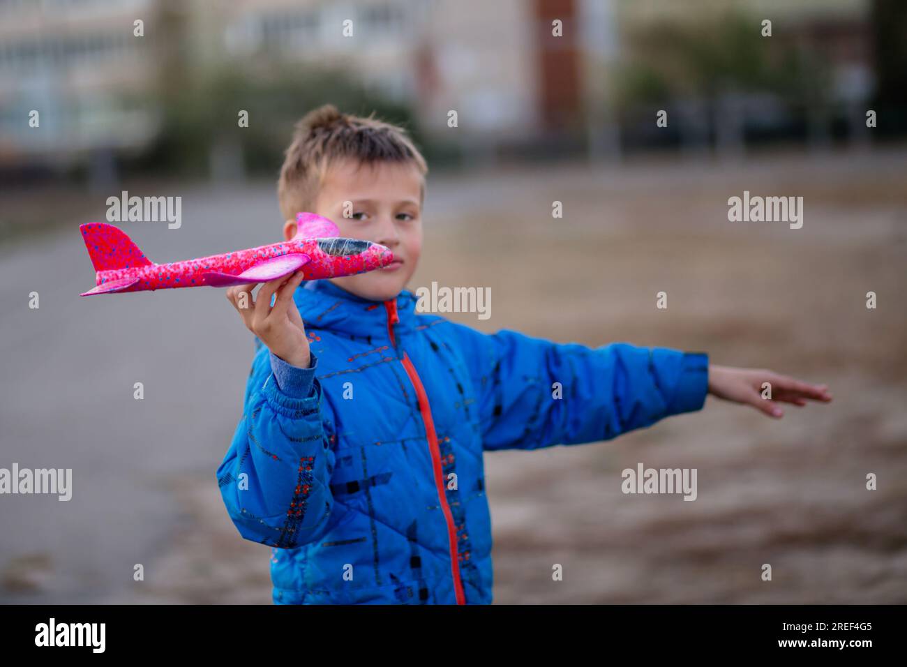 little pilot With a toy airplane in hand at the sports ground. Children's toys for outdoor play in autumn Stock Photo