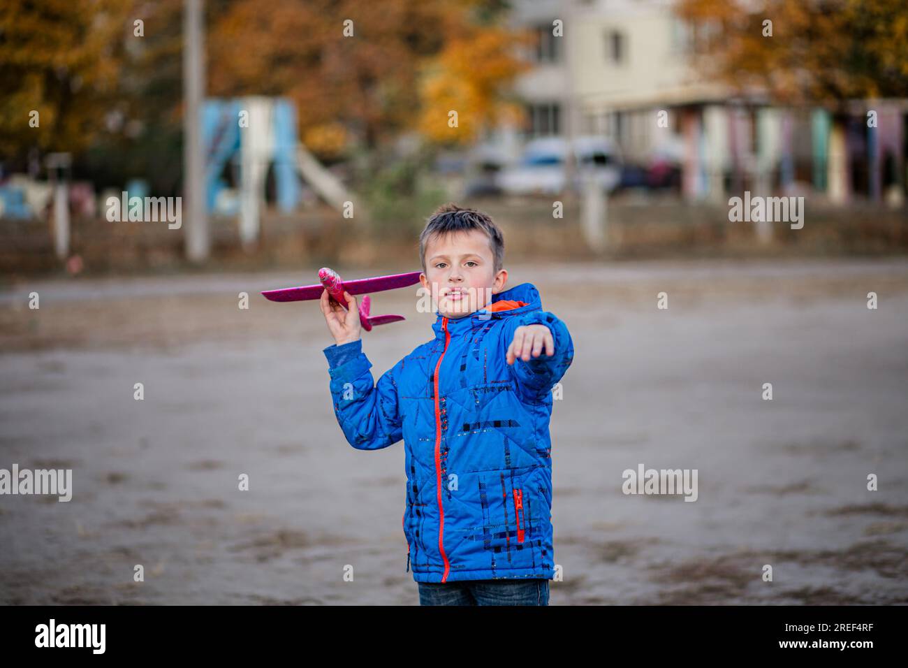 In the fall ambiance, a young boy playfully launches his toy airplane, channeling the spirit of a future pilot. Stock Photo