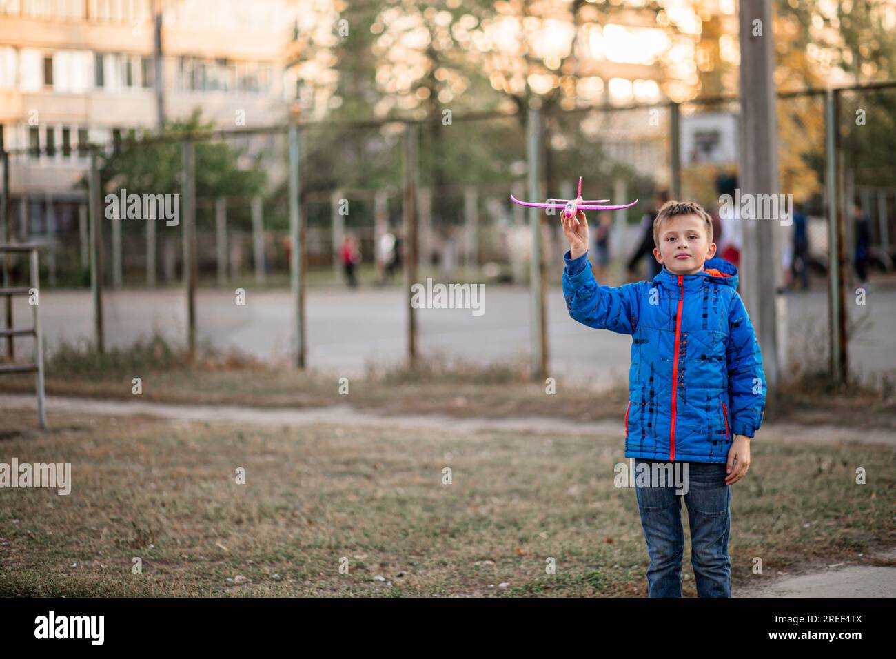 Little aviator's joy! With outstretched arms, the boy releases his toy airplane. Autumn vacation Stock Photo