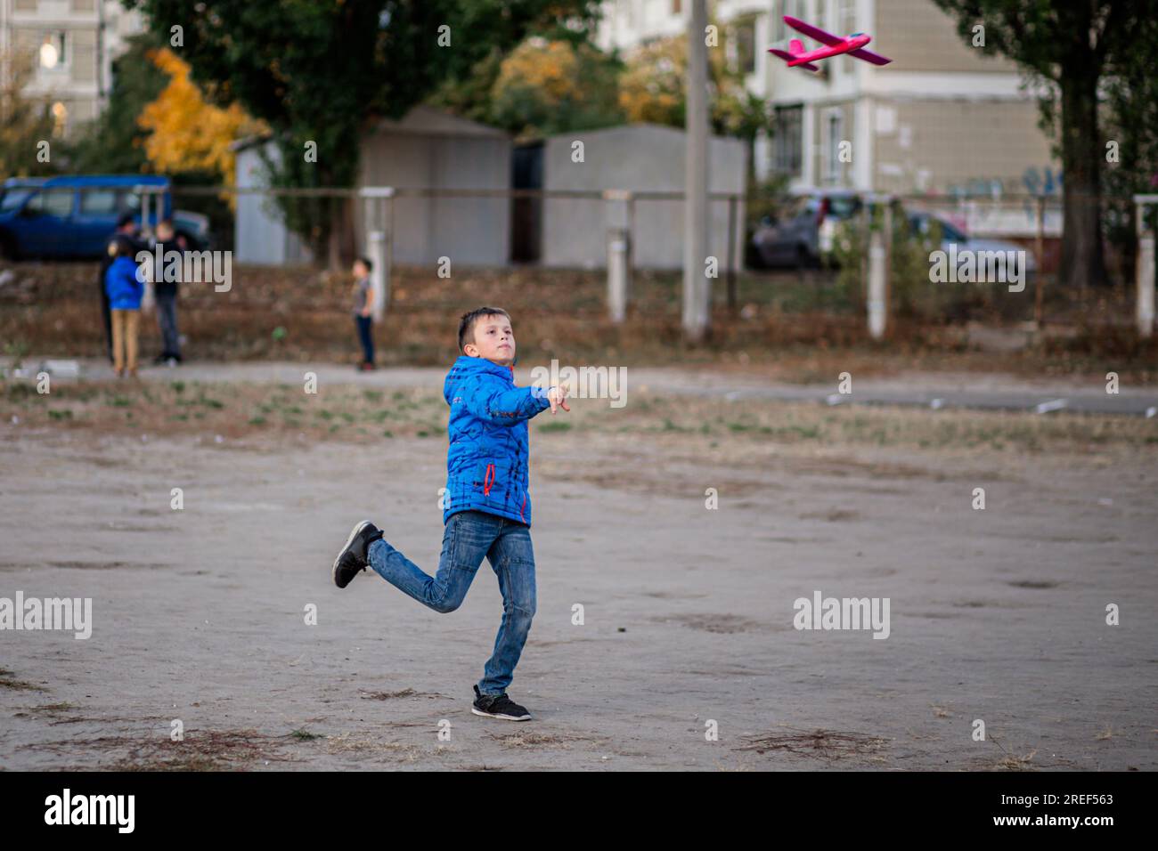 Against the autumn backdrop, a young boy launches his toy plane. Stock Photo