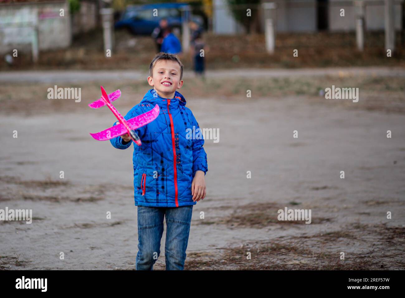boy lets his toy plane take flight on the sports field. Curious boy plays with airplanes. Development of children's imagination Stock Photo