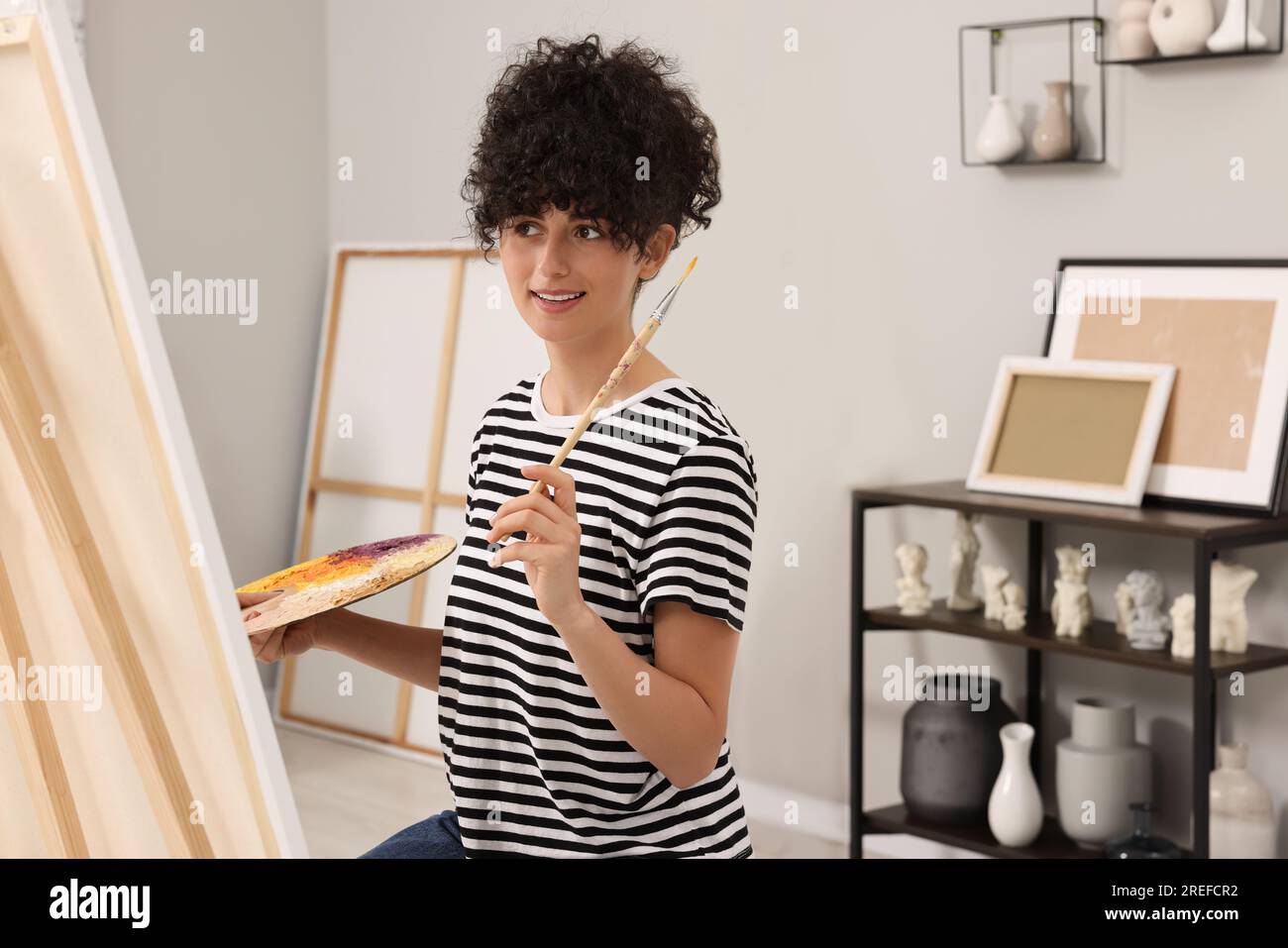 Young woman painting on easel with canvas in studio Stock Photo - Alamy