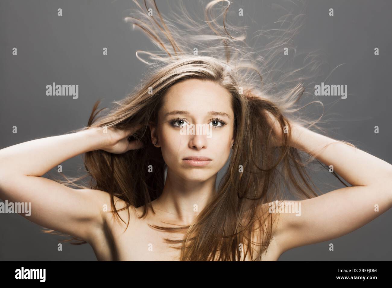 girl with flowing hair in the air studio portrait against gray