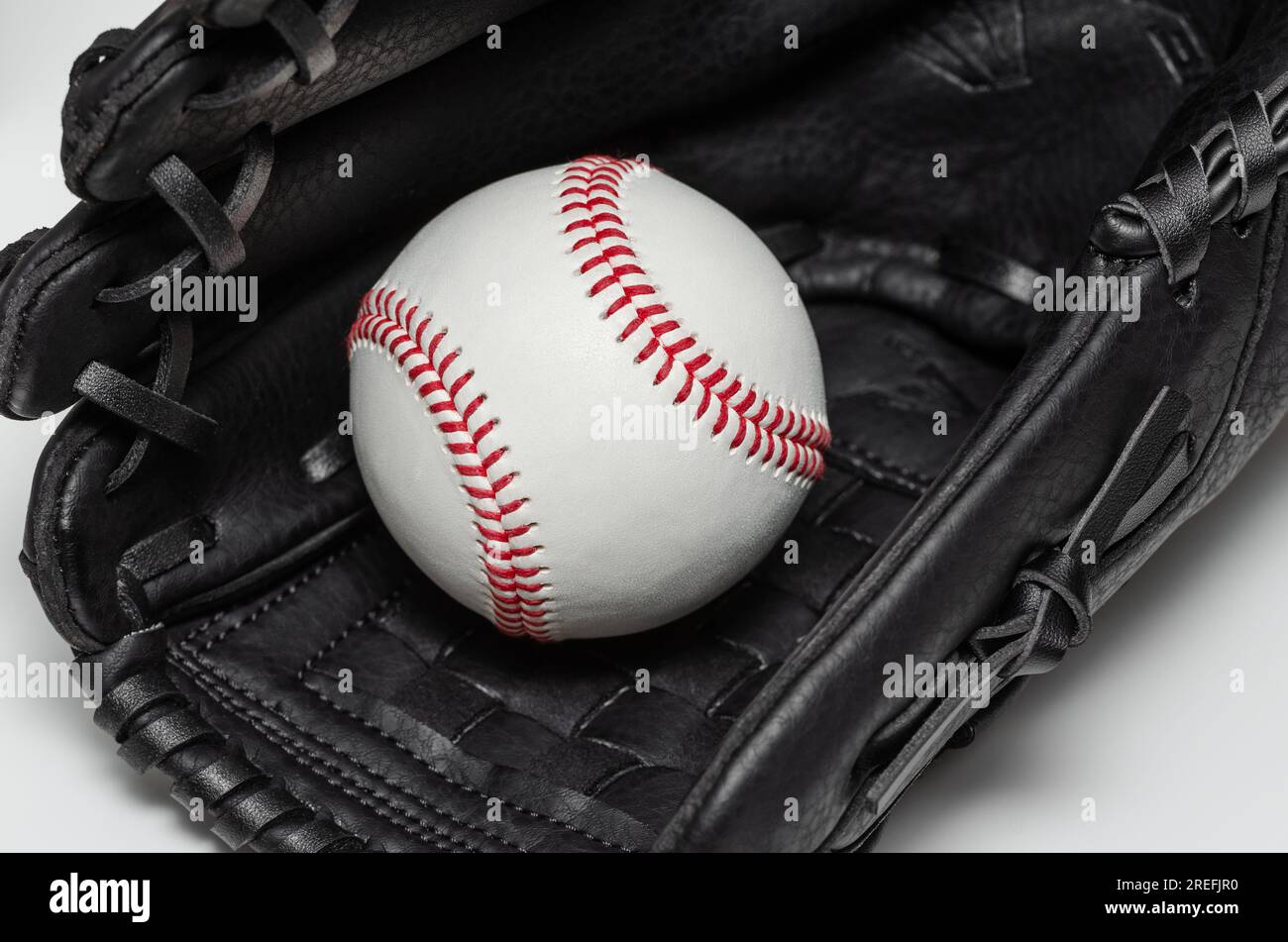 Closeup of a white baseball ball with red stitches inside baseball glove Stock Photo