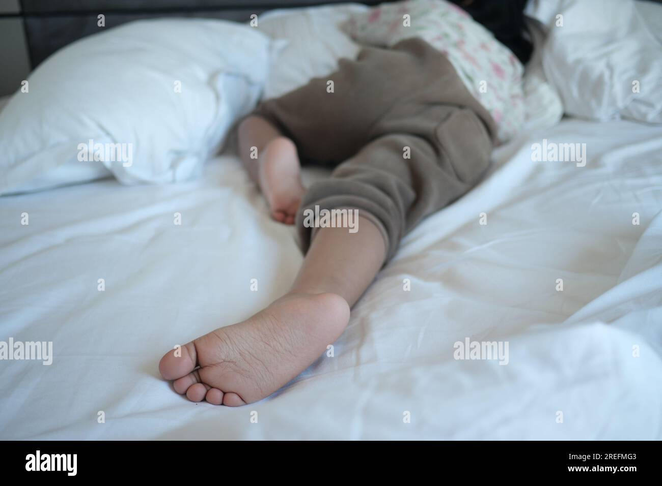 a child sleeping on bed barefoot Stock Photo Alamy