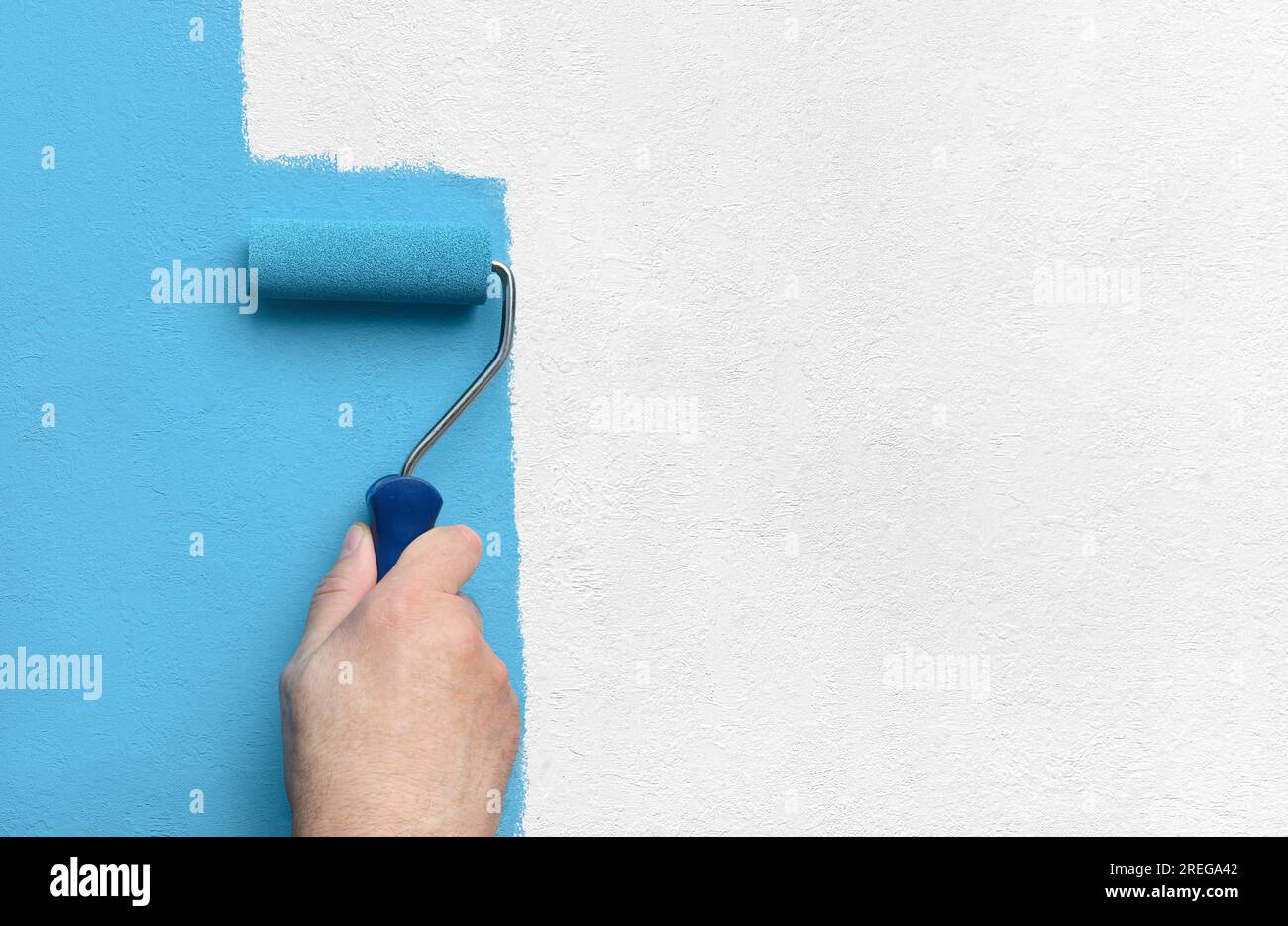 Blue color painting wall with roller in hand Stock Photo - Alamy