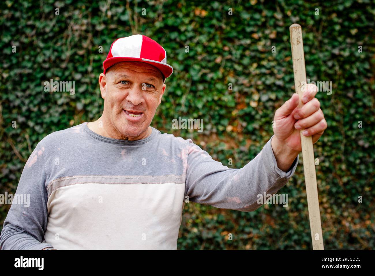 Portrait of a senior man in a ball cap with toothy grin doing yardwork Stock Photo