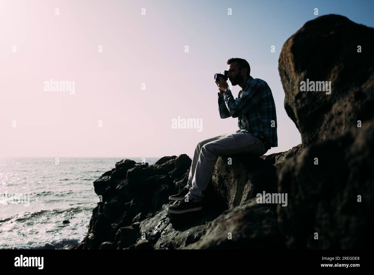 Young boy taking pictures in backlight beside the sea. Stock Photo