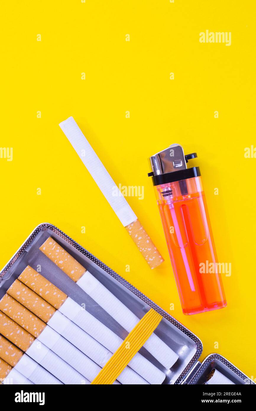 Cigarettes, case and lighter against yellow Stock Photo