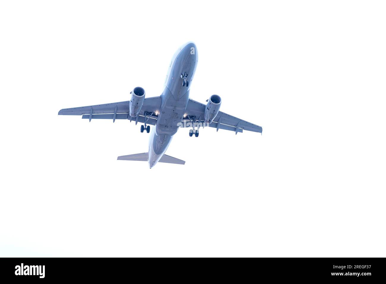 Low angle view of commercial airplane flying in sky with landing gear ready to take off at airport Stock Photo