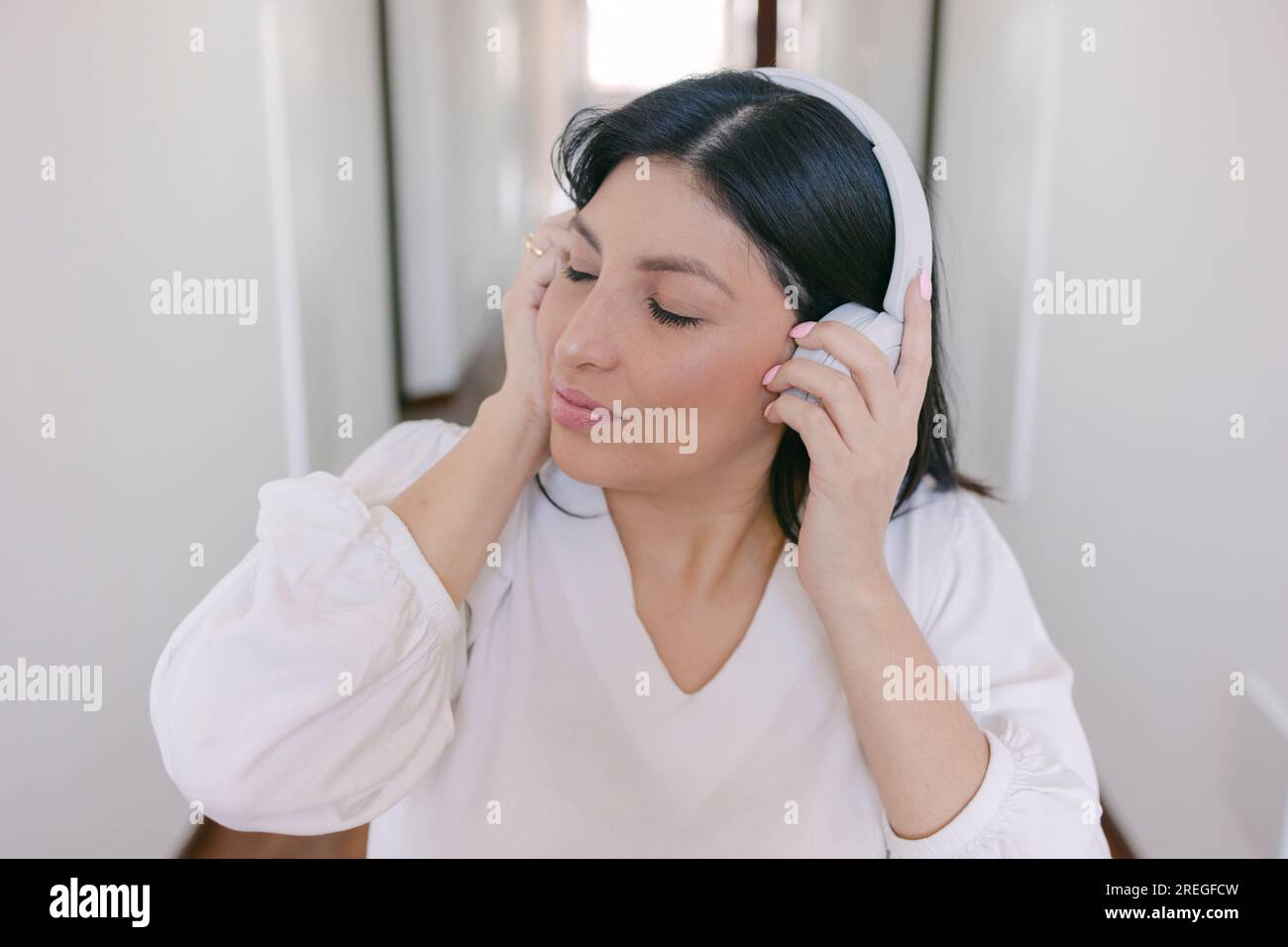 Portrait of cute hispanic girl using headphones and listening to music Stock Photo