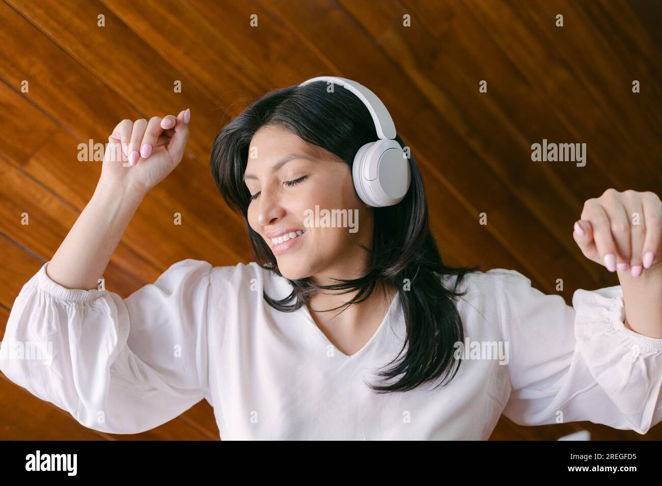 Portrait of cute hispanic girl using headphones and listening to music ...