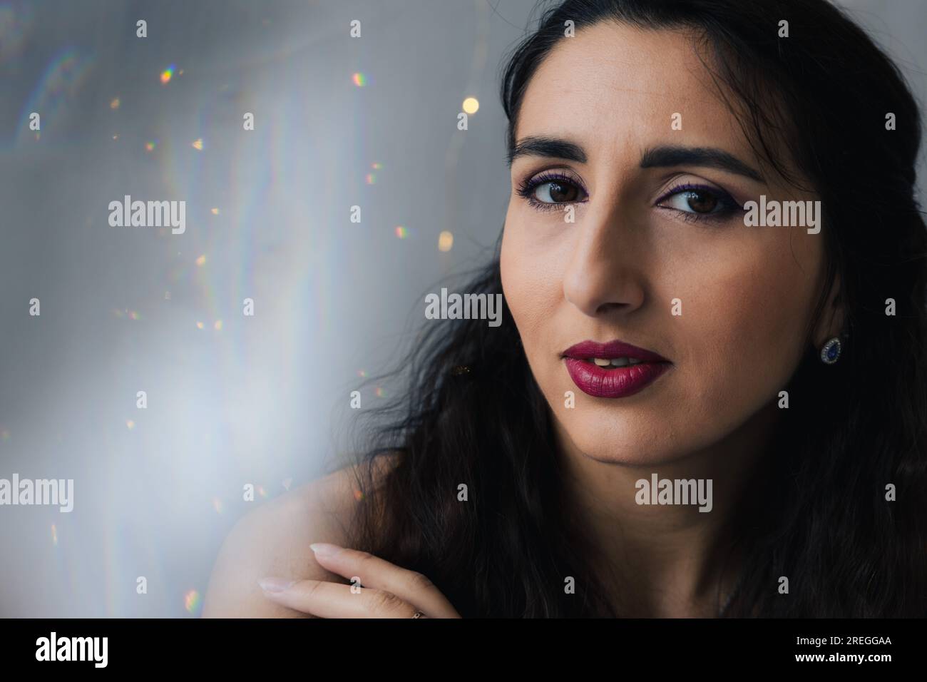 Close-up of a girl on a gray background with twinkle lights Stock Photo