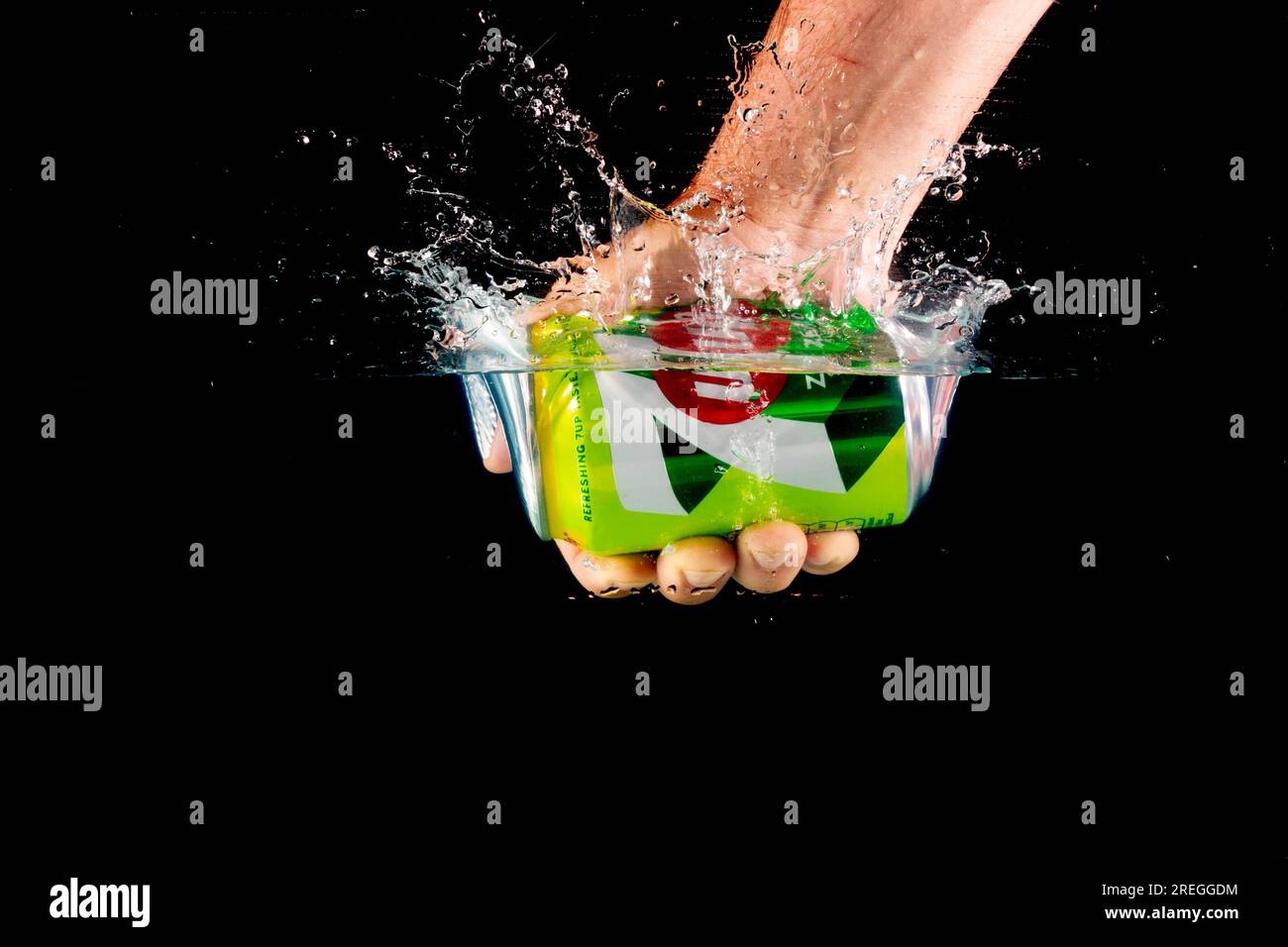 London, United Kingdom, 24th July 2023: A Can of 7up held in a hand splashing into water against a black background Stock Photo