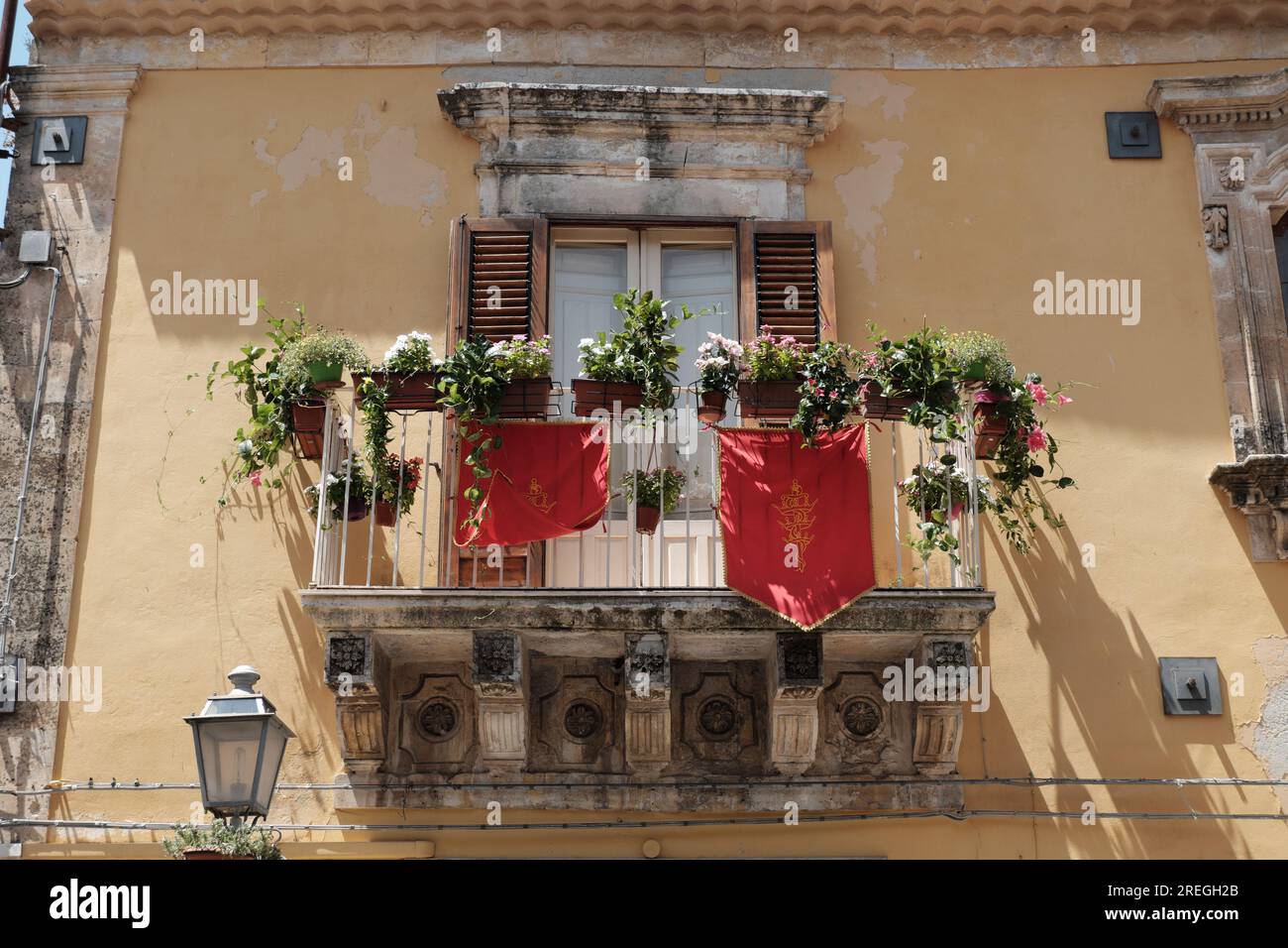 baroque balcony of Palazzo Pizzo with the gonfalon of San Paolo Apostolo in Palazzolo Acreide, Sicily, Italy Stock Photo