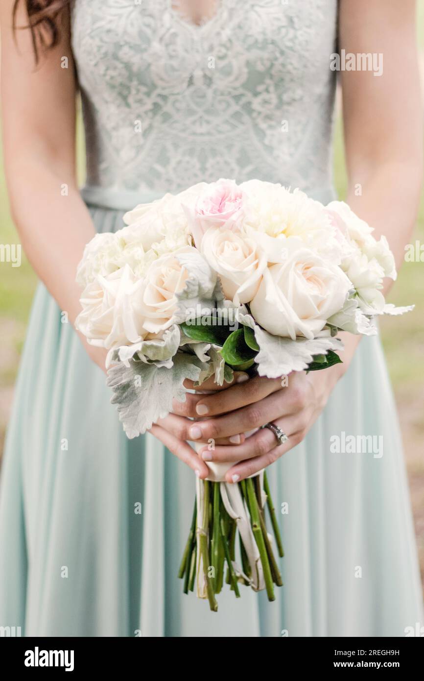 Close up of flower bouquet in hands of bridesmaid in teal dress Stock Photo