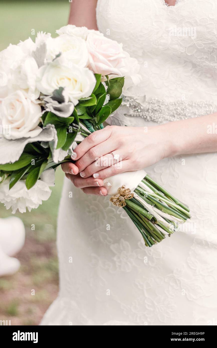 Close up of wedding bands on bride's hand while holding bouquet Stock Photo