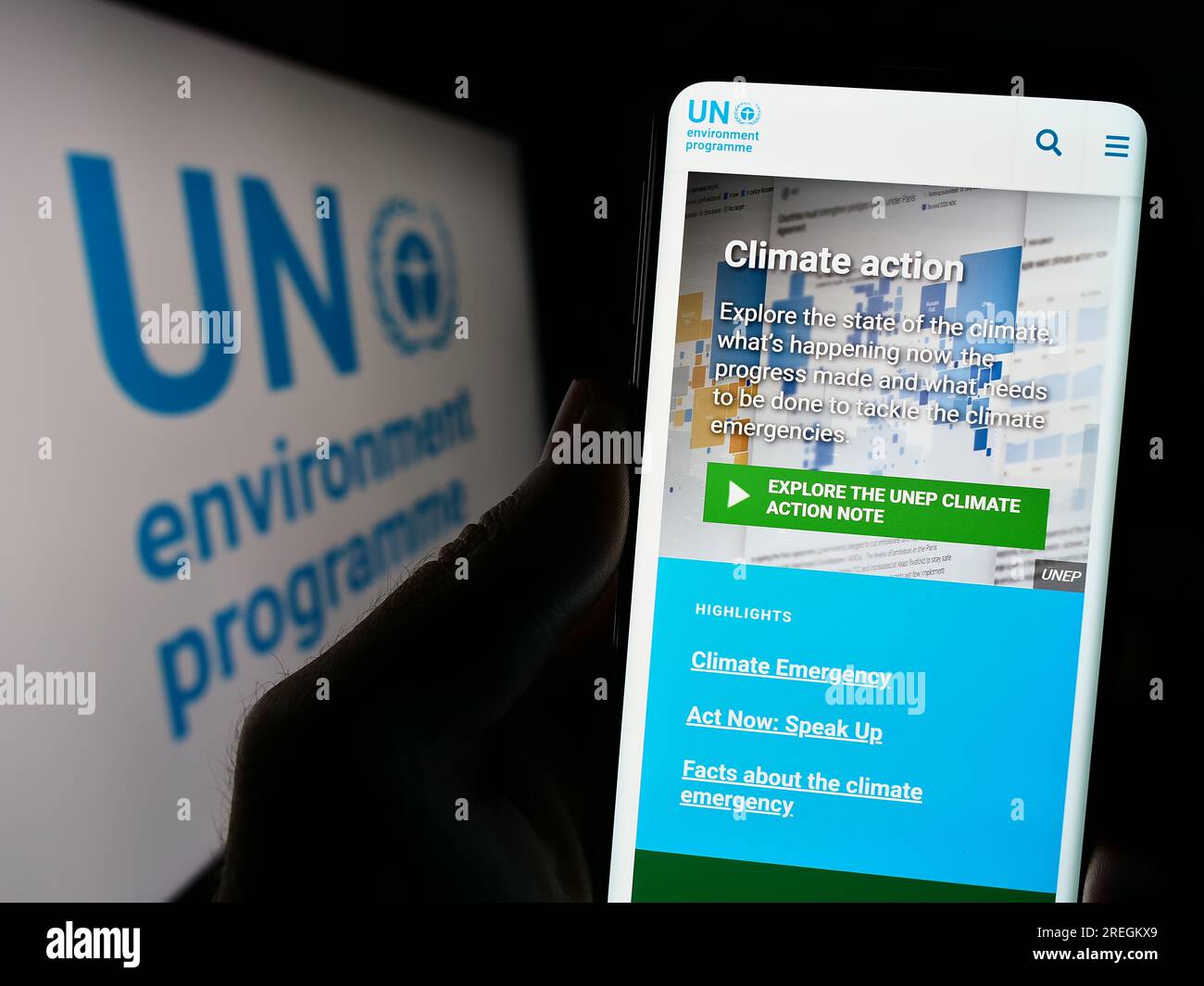 Person holding cellphone with website of United Nations Environment Programme (UNEP) on screen in front of logo. Focus on center of phone display. Stock Photo
