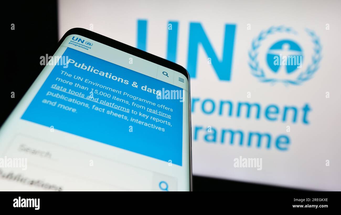 Smartphone with webpage of United Nations Environment Programme (UNEP) on screen in front of logo. Focus on top-left of phone display. Stock Photo