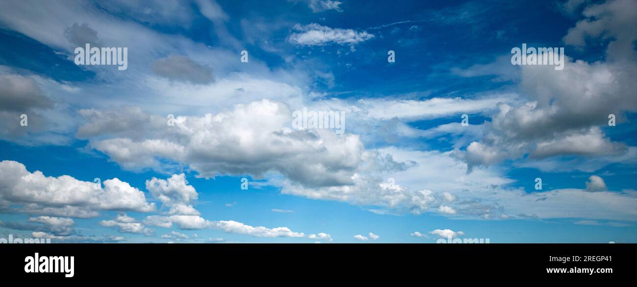 Panoramic view of a blue sky with white and gray fluffy clouds. Stock Photo