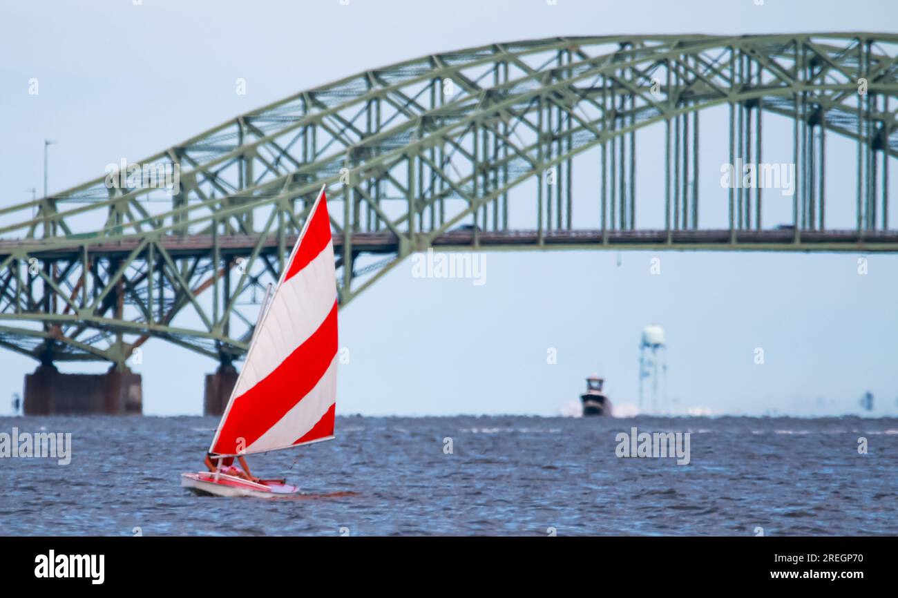 Front view of a close up of one red and white sunfish sailboat sailing on  the Great South Bay with the bridge close in the background Stock Photo -  Alamy
