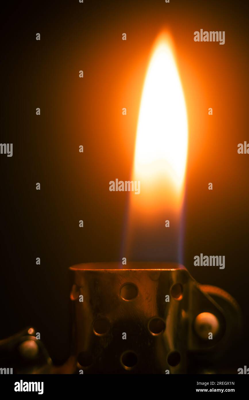 Lighter with a bright flame in a dark room Stock Photo