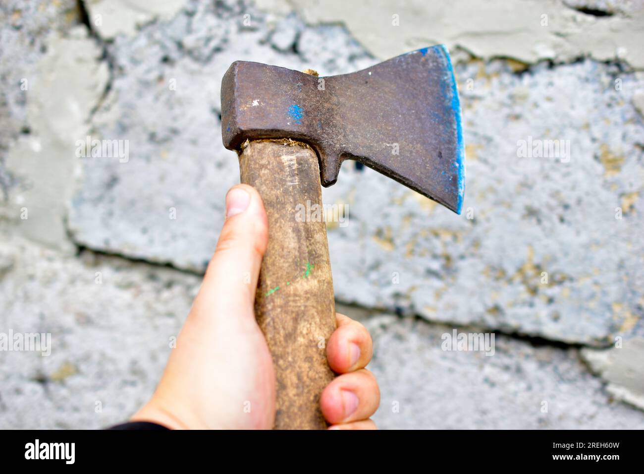 An axe in the hands of a man against the wall Stock Photo