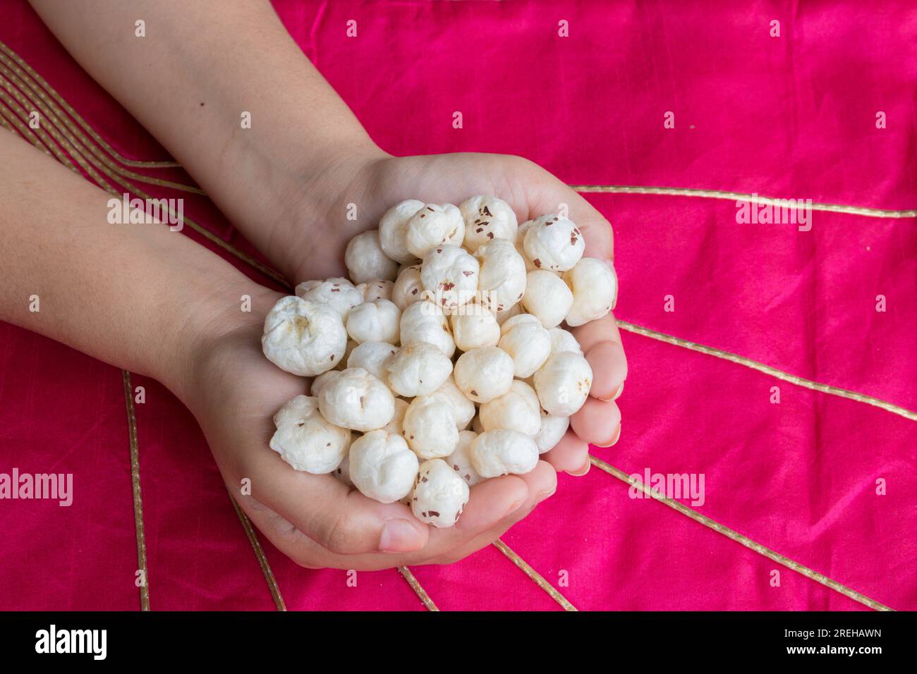 Makhana or foxnut in hand with pink background Stock Photo