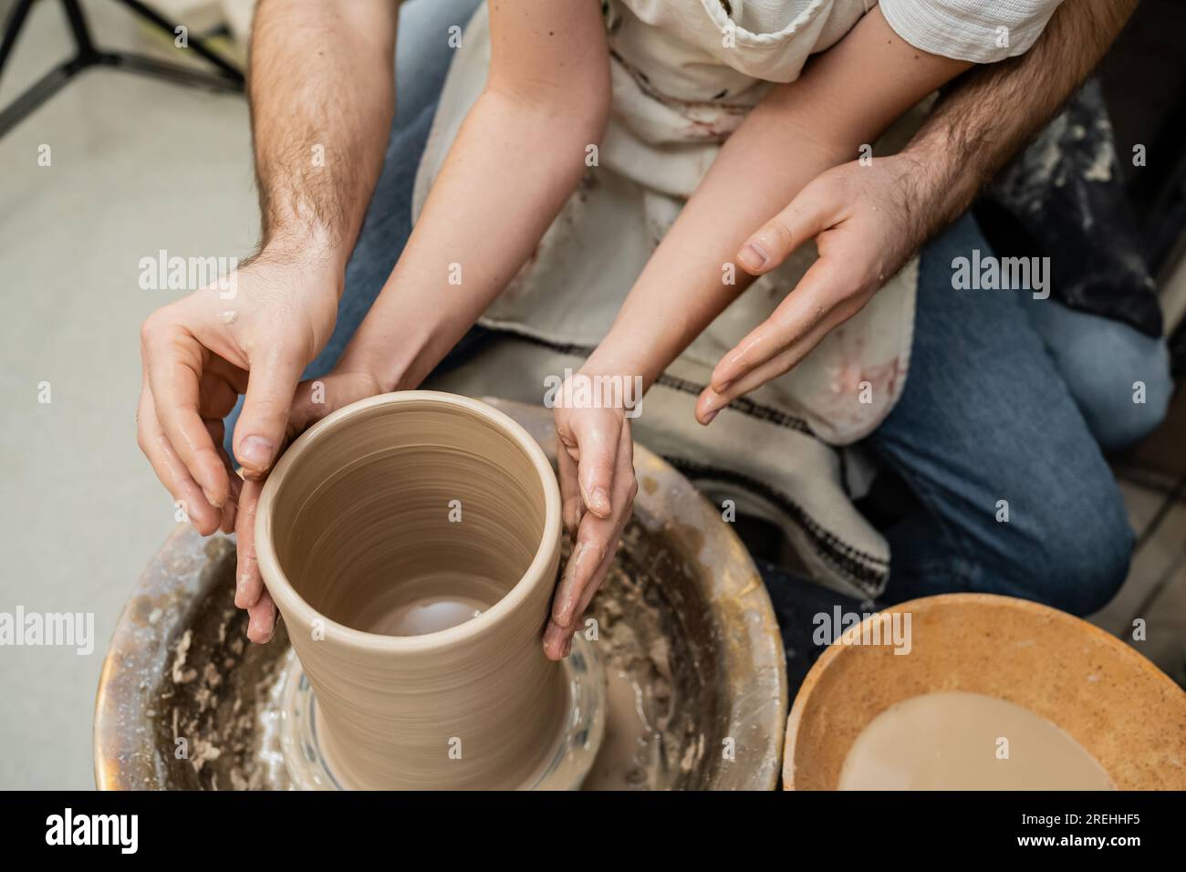 Cropped view of romantic couple of potters making clay vase on pottery wheel in ceramic
