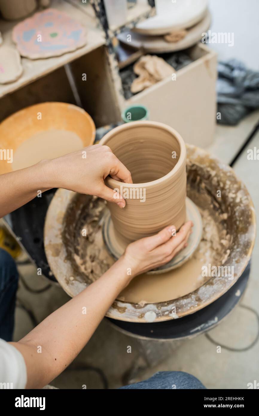 High angle view of female artisan making clay vase on pottery wheel in ceramic workshop Stock Photo