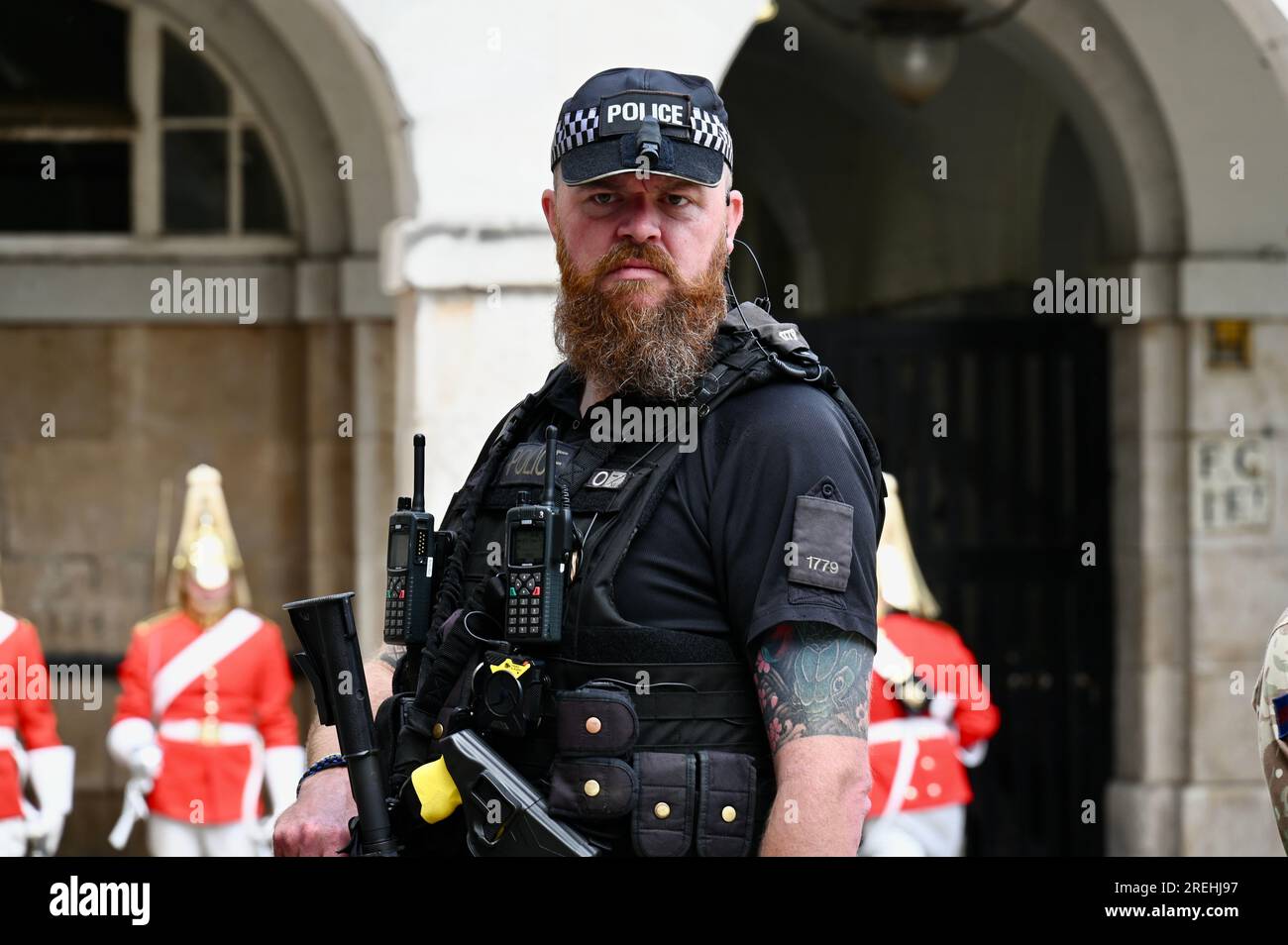 Armed Police Officer protecting the Changing of the King's Life Guard , Horse Guards Parade, Whitehall, London, UK Stock Photo