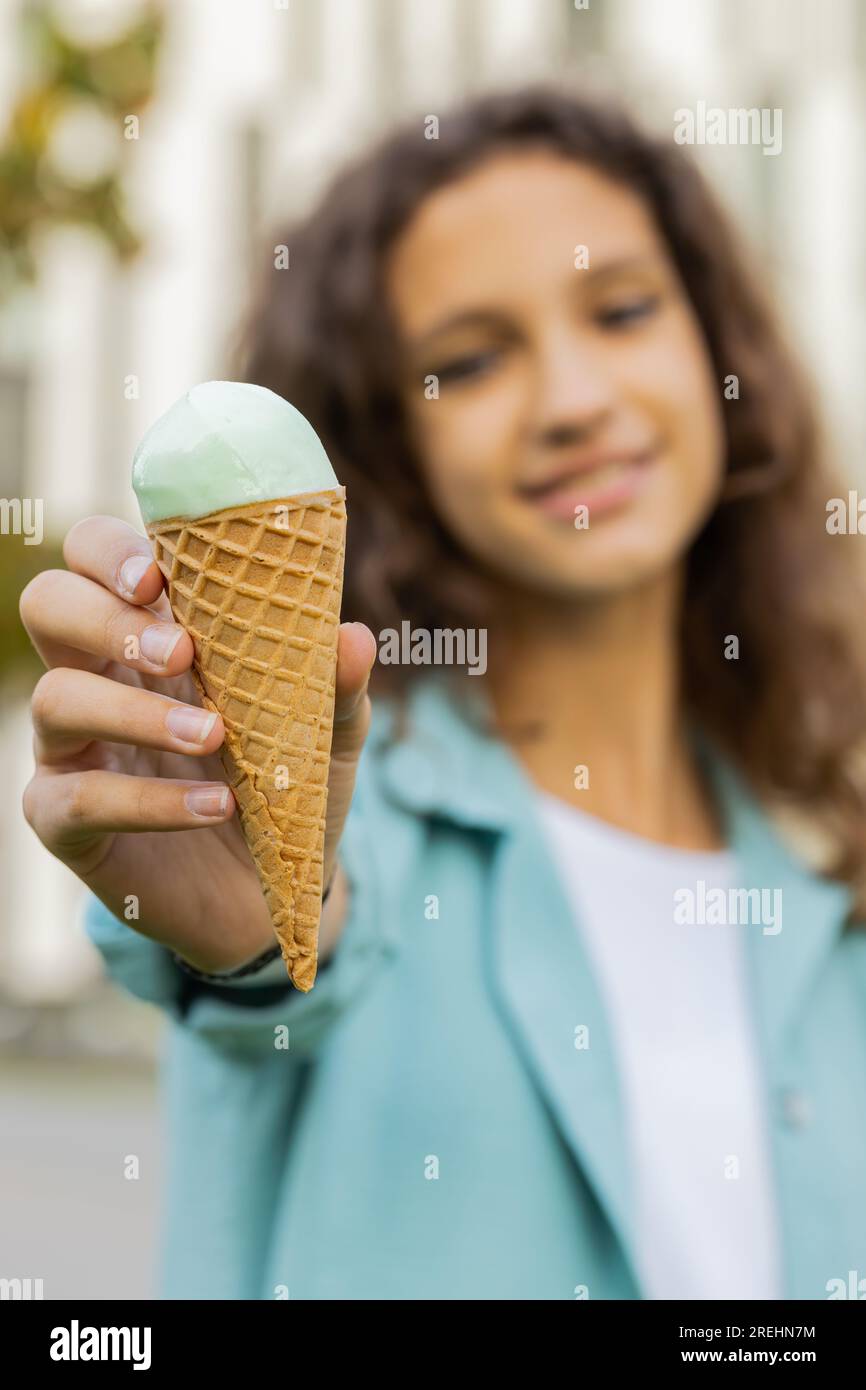 Preteen child kid standing showing eating ice cream in waffle cup. Cute