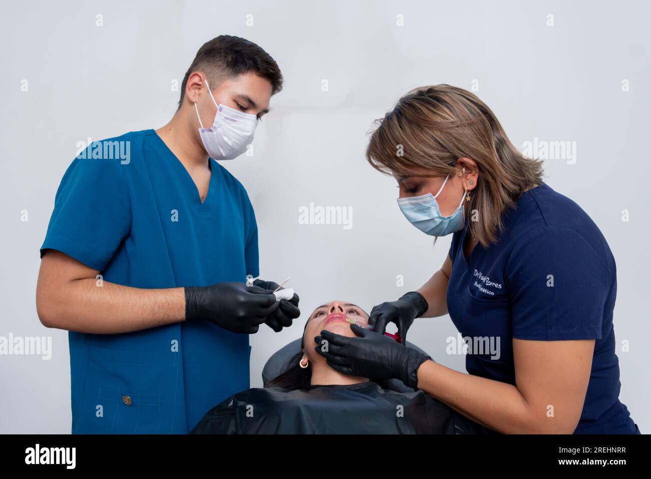 Esthetician doctors apply hyaluronic acid lip filler to a young woman