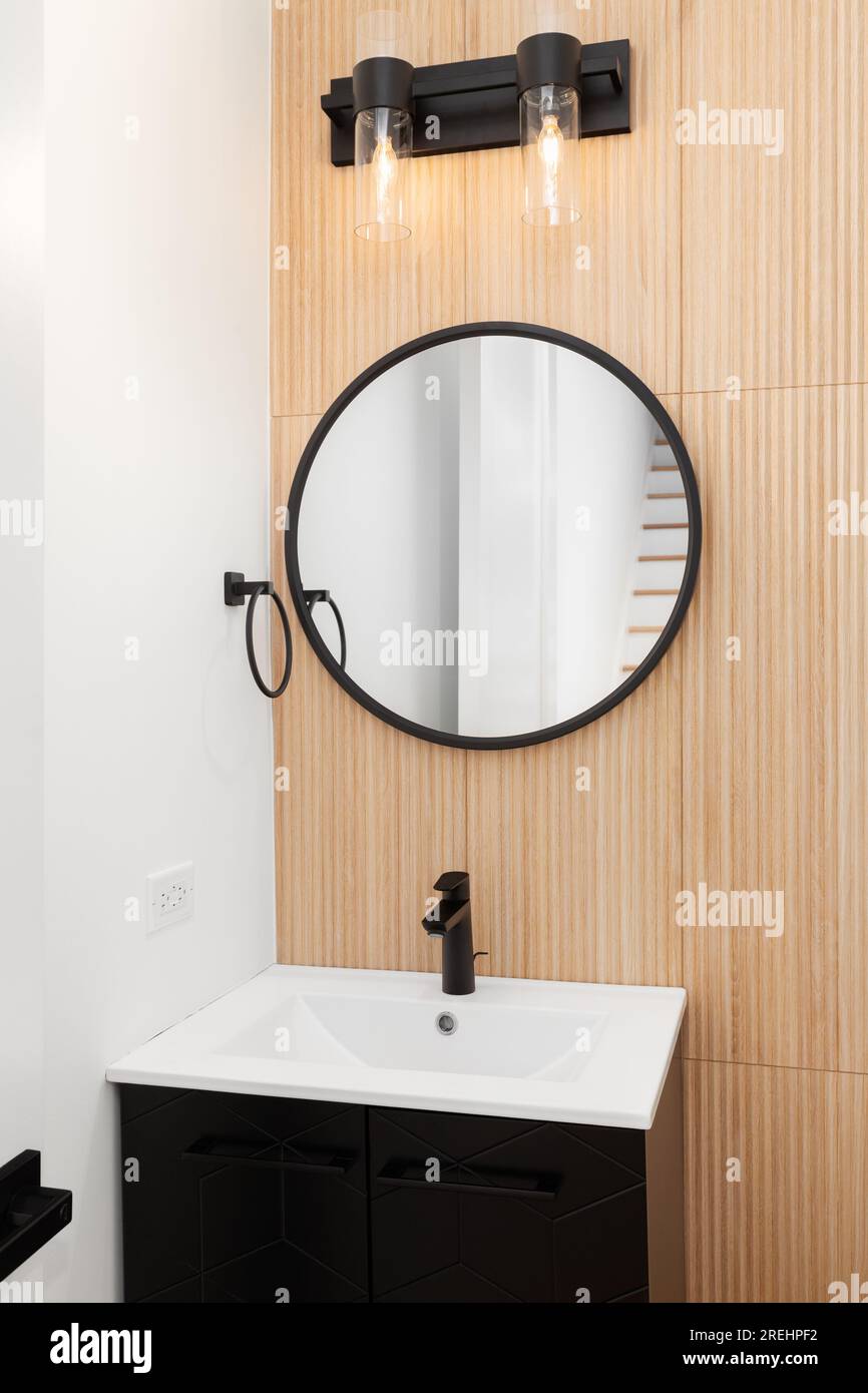 A bathroom with a white oak wood slat wall with a black and