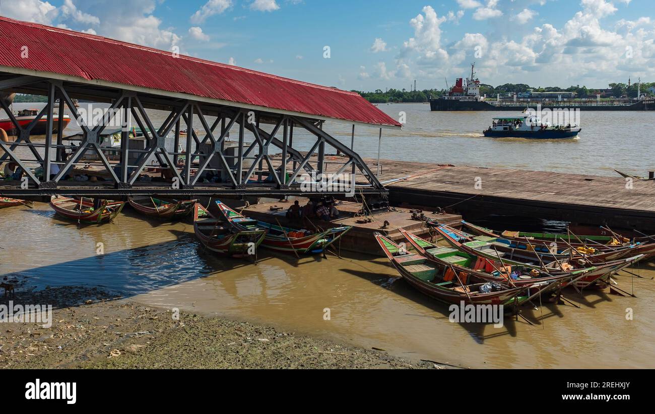 Rangoon, Myanmar, 2014. Several row boats neatly docked under the Botahtaung gangway on the Yangon River Stock Photo