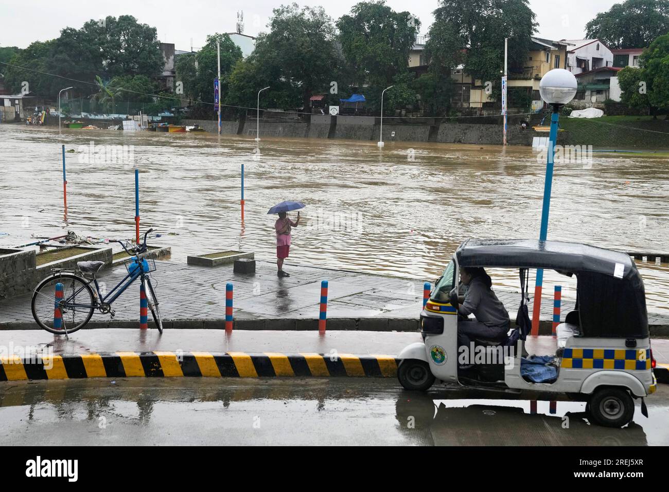 A man takes a picture of a swollen river due to enhanced rains brought ...