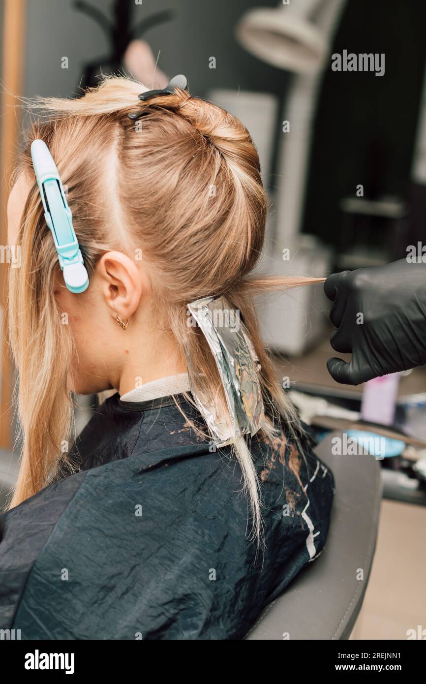 The process of hair coloring in a beauty salon. Blonde dyeing her hair ...