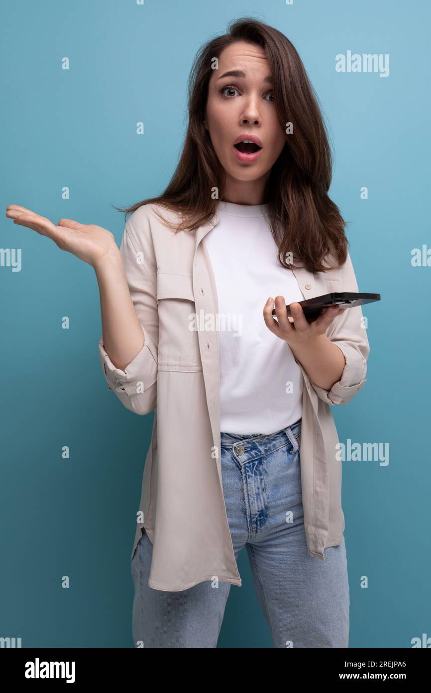 surprised adorable brunette 30 year old female person in shirt and jeans  with smartphone Stock Photo - Alamy
