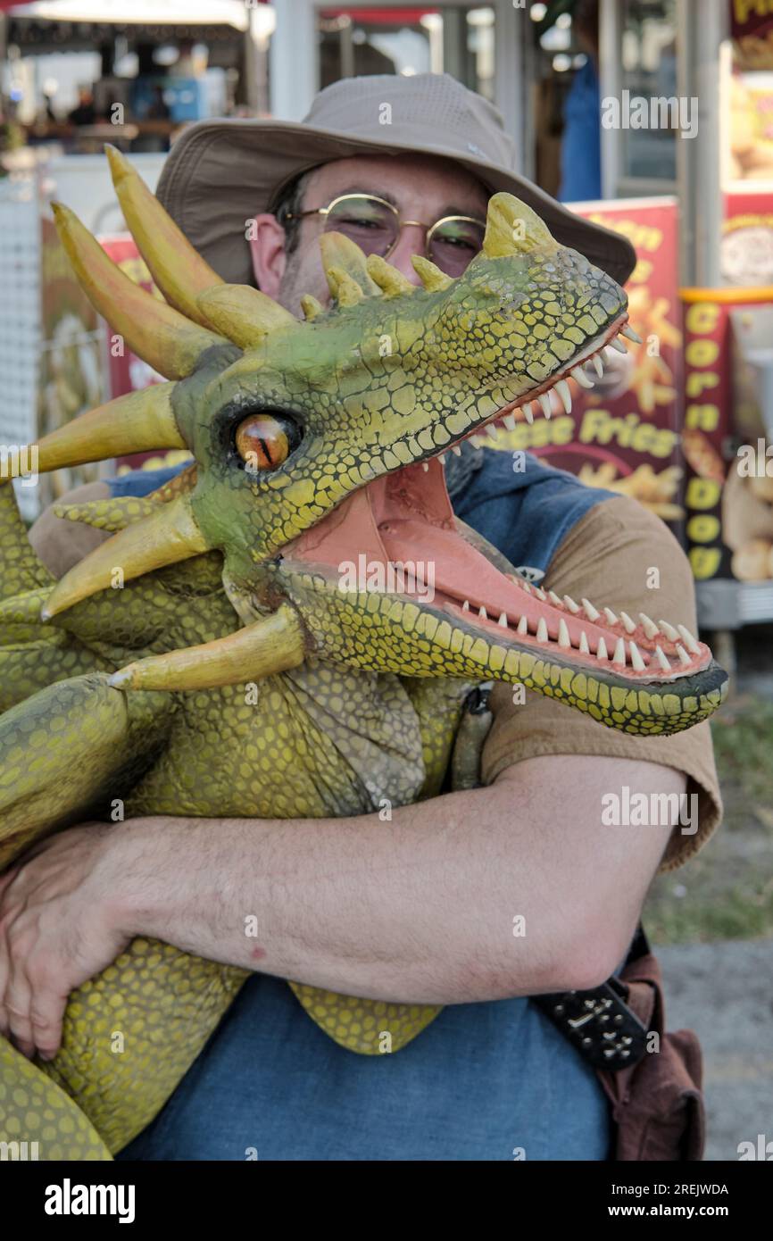 Puppeteer strolls the midway with a dinosaur puppet at the 2023 Delaware State Fair, Harrington, Delaware USA. Stock Photo