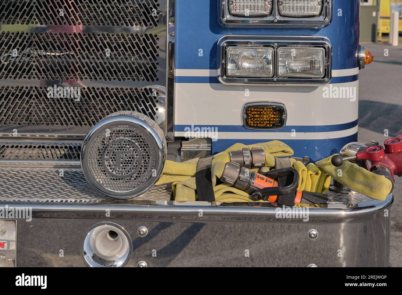 Hoses, siren, and valves on front bumper of a blue fire engine pumper truck. Stock Photo